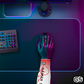 Close-up of a hand using a mouse while wearing a colorful compression gaming sleeve, shown in an RGB-lit gaming and streaming setup.